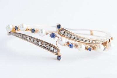 Lot 65 - A 14ct  Gold Continental Sapphire, Diamond & Seed Pearl Crossover Bangle Bracelet